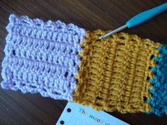 two crocheted squares are next to each other on a table with a notepad