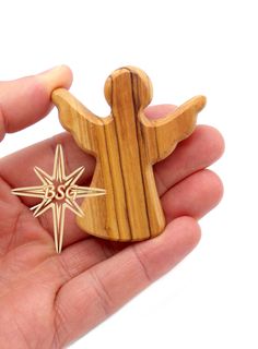 a hand holding a wooden ornament with a star on it