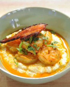 a bowl filled with shrimp and grits on top of a wooden table