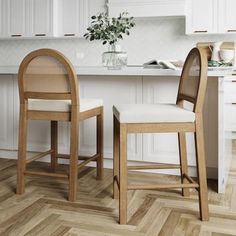 two wooden chairs sitting next to each other on top of a hard wood floor in a kitchen