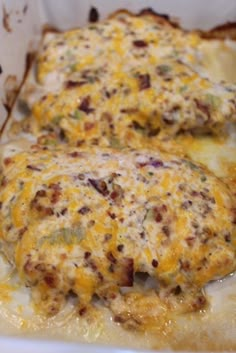 two pieces of meat covered in cheese and other toppings on top of a casserole dish