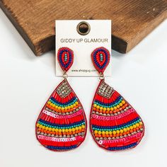 These are multicolored teardrop earrings with a mix  of beads and crystals. There is a mix of different  sizes and colors of beads such as orange, red, blue,  yellow, pink, and turquoise. There is also sequins  and crystals. These earrings are taken on a white  background and leaned up against a brown block. Crystal Teardrop Earrings, Giddy Up Glamour, Cute Earrings, Teardrop Earrings, Handmade Jewelry, Drop Earrings, Crystals, Handmade Jewellery