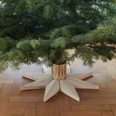 a small tree in a wooden vase on the floor next to a wood flooring pattern