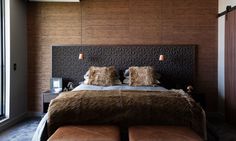 a large bed with two pillows on top of it next to a wooden headboard