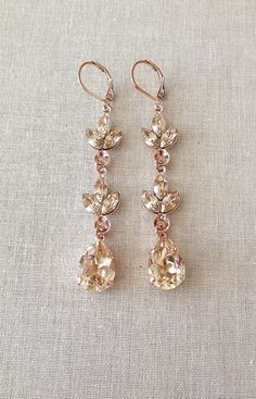 "Stunning pair of long earrings featuring pale champagne marquise crystal leaves leading down to a 14x10mm pear cut crystal. 2 7/8\" long. Rose gold metal finish." Champagne Jewelry, Champagne Earrings, Champagne Rose, Large Statement Earrings, Gold Chandelier Earrings, Earrings Chandelier, Prom Earrings, Rose Gold Crystal, Earrings Bridesmaid