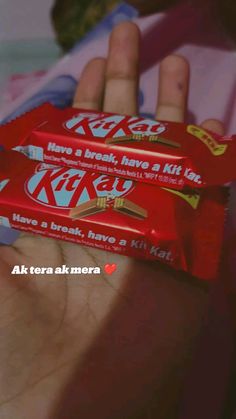 a person holding two packets of kitkats in their hand