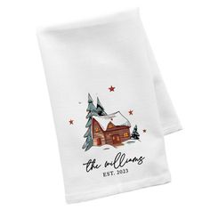 two white napkins with a house and trees on the front, one is for christmas