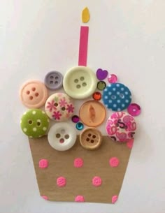 a cupcake decorated with buttons and a candle