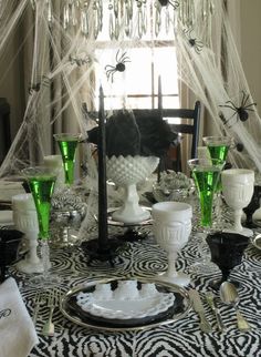 a dining room table decorated for halloween with spider webs and candlesticks on it