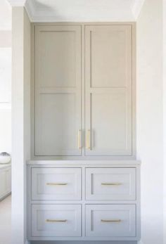 an empty room with white cabinets and drawers