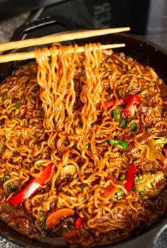 noodles being cooked in a skillet with chopsticks sticking out of the top