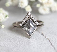 a diamond ring sitting on top of a table next to white flowers and greenery