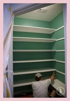 a man is painting the walls of a closet with green paint and white shelving