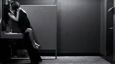 a man and woman kissing in front of a mirror while sitting on a bathroom sink