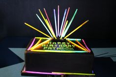 the birthday cake is decorated with neon sticks