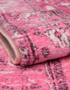 a pink rug with black and white designs on it is laying on top of the floor