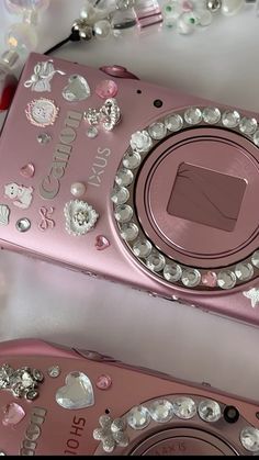 a pink camera sitting on top of a table next to beads and other things around it