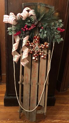 an old wooden sled with christmas decorations and ribbon tied around the wreath on top