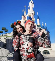 a man and woman posing for a photo in front of the castle at disney world