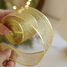 a person is holding a roll of gold ribbon