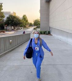 a woman walking down a sidewalk wearing a face mask