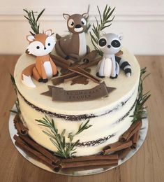 a cake decorated with three little raccoons on top of a wooden table next to an arrow