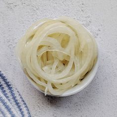 a white bowl filled with sliced onions on top of a table