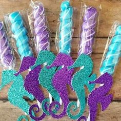 mermaid cake toppers with purple and blue icing on wooden table next to cupcakes