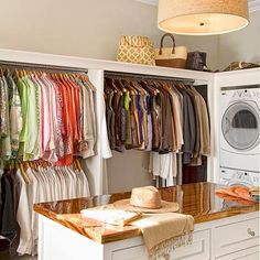 an organized closet with clothes on hangers and a washing machine in the corner next to it