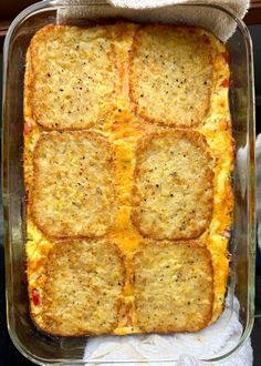 a casserole dish with cheese and vegetables in it on a towel next to a glass container