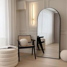 a large mirror sitting on top of a wooden floor next to a chair and ottoman