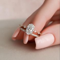 a woman's hand holding an engagement ring with diamonds on the band and side stones