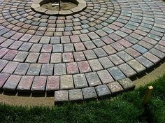 a circular brick fire pit in the middle of a grassy area next to a tree