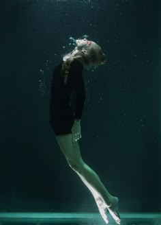 a woman in black shirt and shorts diving under water