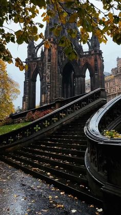 an old building with stairs leading up to it and autumn leaves on the ground below