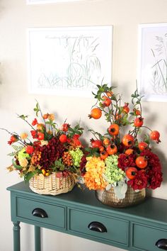 two baskets filled with flowers sitting on top of a green table next to a wall