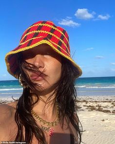 a woman wearing a red and yellow hat on the beach