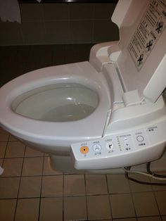 a close up of a toilet with buttons on the lid