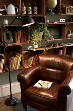 a brown leather chair sitting in front of a book shelf next to a lamp and bookshelf