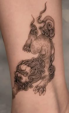 a woman's leg with a tattoo design on it, depicting a chinese dragon