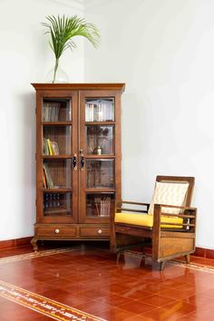 a wooden chair sitting next to a book case on top of a red tile floor