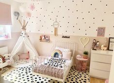 a child's bedroom decorated in pink and white with polka dots on the walls