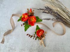 three flowers and two stalks of wheat on a white tablecloth with brown ribbon around them