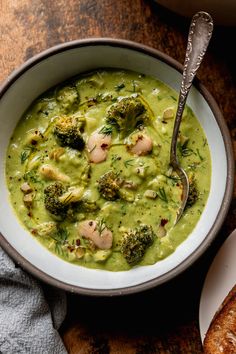 a bowl filled with broccoli and chicken soup next to a piece of bread