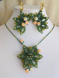 a necklace and earring set made out of beaded flowers on a mannequin