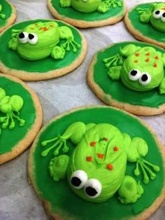 cookies decorated with green frosting and googly eyes are arranged in the shape of frogs