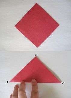 someone is making an origami kite out of red paper and then fold it in half