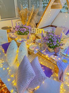 the table is set with purple flowers and white linens for an elegant dinner party