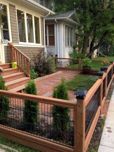 a fenced in yard with grass and bushes on the side walk next to a house