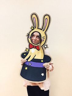 a woman holding up a cardboard cutout of a cartoon rabbit wearing a top hat